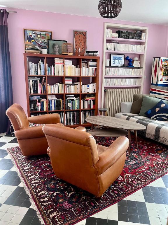 a living room with leather chairs and a table and bookshelves at Maisonnette Clisson quartier Trinité in Clisson