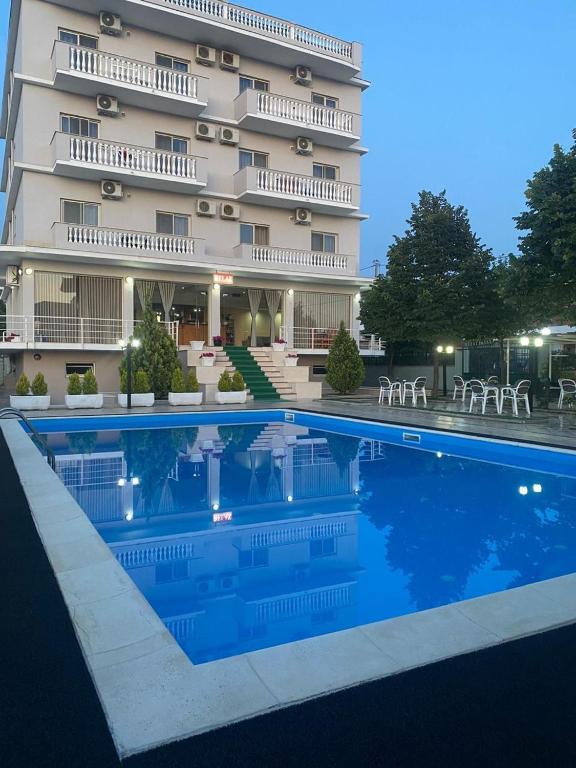 a hotel with a swimming pool in front of a building at Relax Apartment & Hotel in Golem