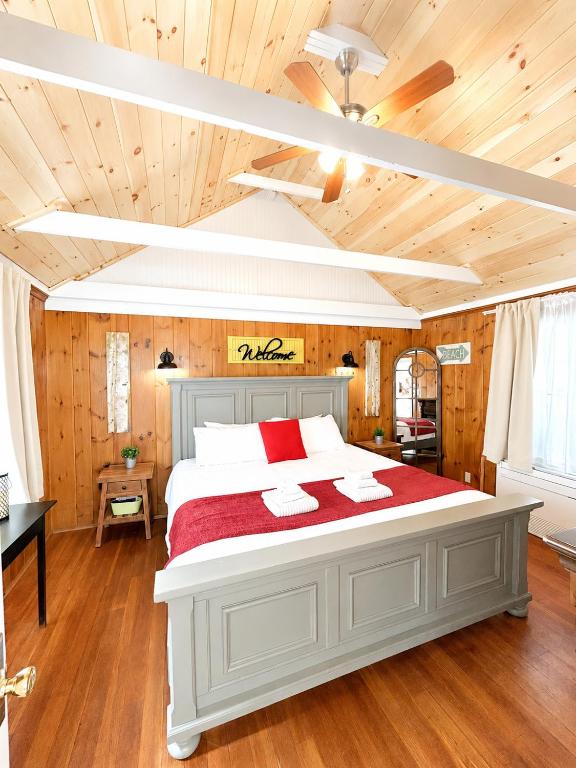a bedroom with a large white bed with red sheets at Cottage 12 - King Bed Child Loft w Twin Private Bath Kitchenette Pets Allowed Fee applies in Wolfeboro