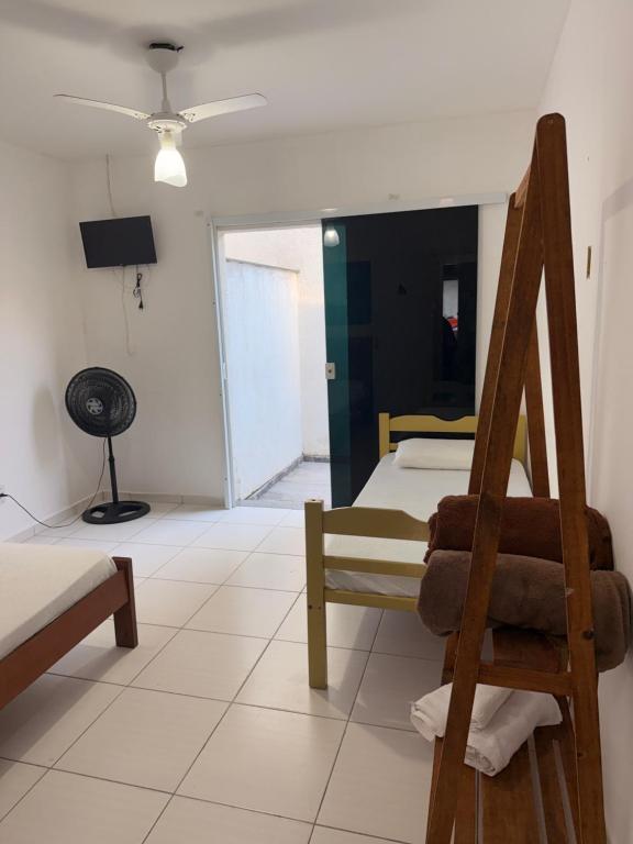 a room with two beds and a chair and a fan at Pousada canto do forte in Cabo Frio