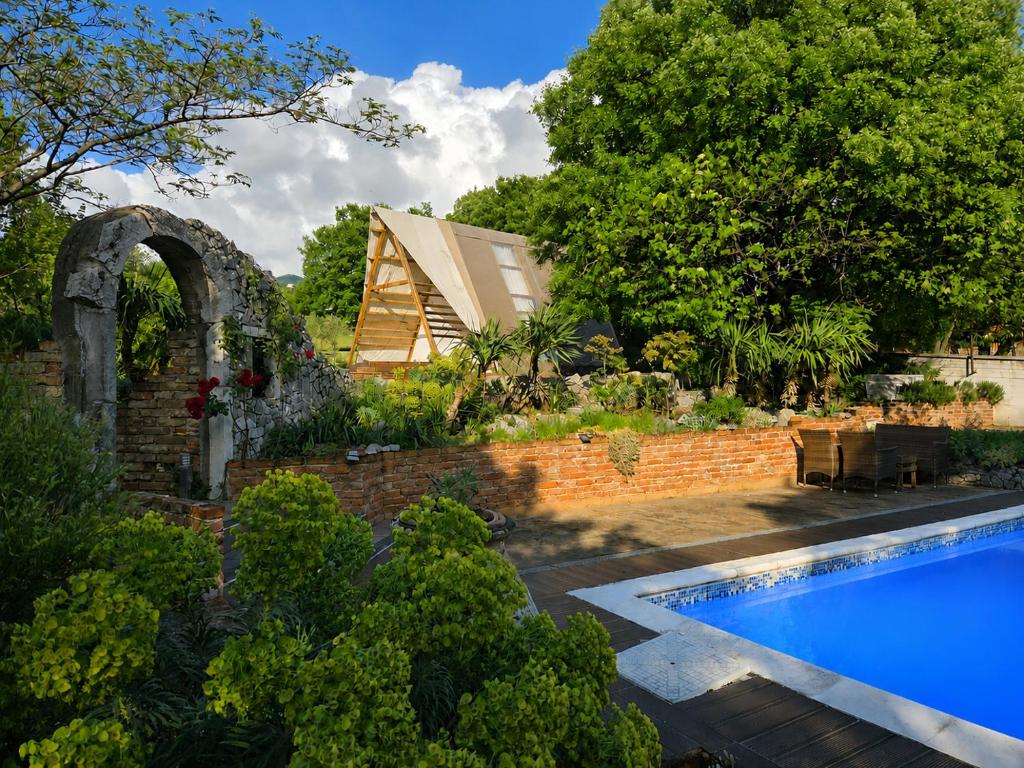 a garden with a swimming pool and a house at Green Glamping Paravia in Krasica