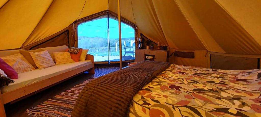 a tent with a bed and a couch in a room at Ardennes Prestige Glamping in La Neuville-aux-Joûtes