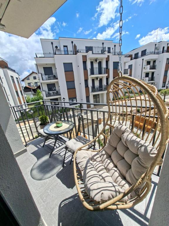 a balcony with a swing and a table and a building at Apartman Merry Lux in Vrnjačka Banja