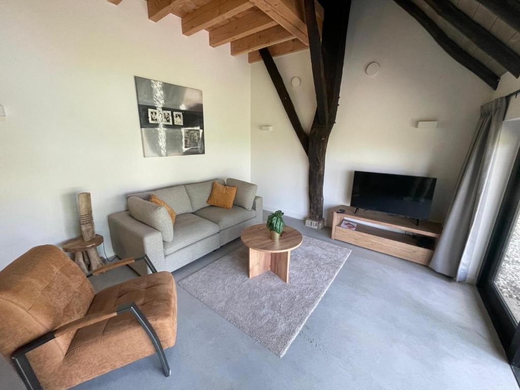 a living room with a couch and a tv at Hoeve 't Peerdeke in Breda