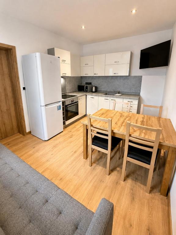 a kitchen with a wooden table and a white refrigerator at M3-Apartmány in Martin