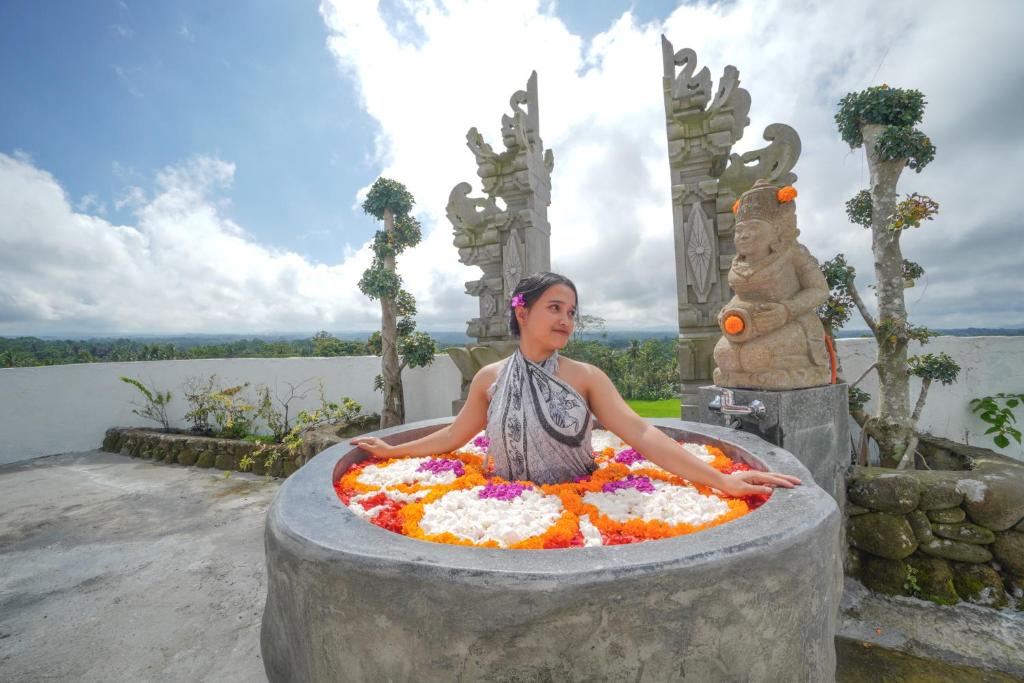 a woman sitting in a bath tub with flowers at The Alugara Suite & Spa in Tegalalang