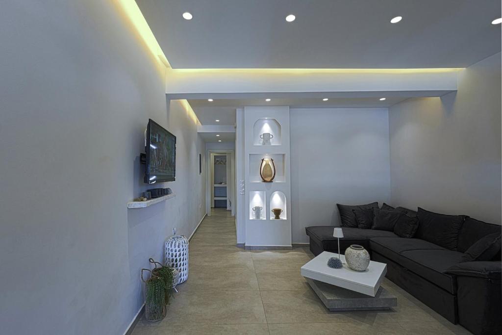 a living room with a couch and a tv at Lontos Luxury Seaside House in Flampouria