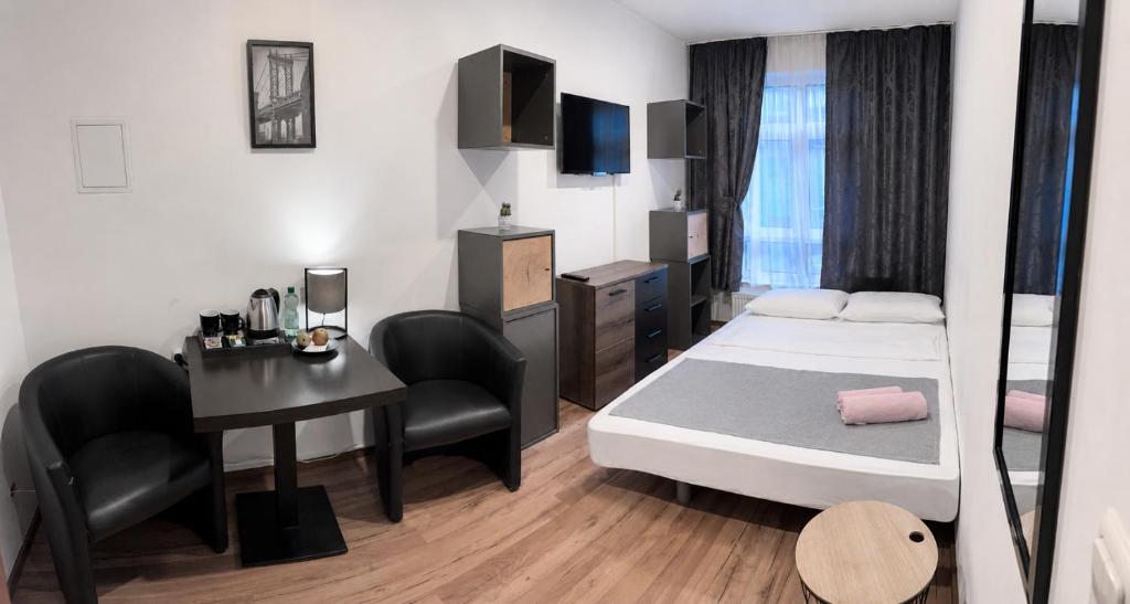 a bedroom with a bed and a desk and a table at Pension Ksenija Hanau in Hanau am Main