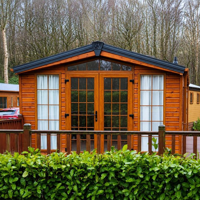 a large wooden cabin with a fence and bushes at Brae Lodge Dollar in Dollar