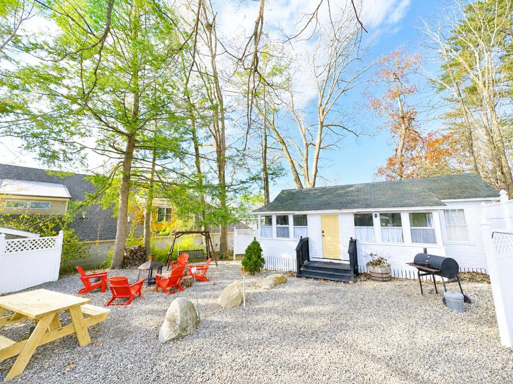 a backyard with chairs and a table and a house at Cottage 8-9 - Stand Alone 2 Bedroom 2 Bath Private Courtyard Pet Friendly with Fee in Wolfeboro