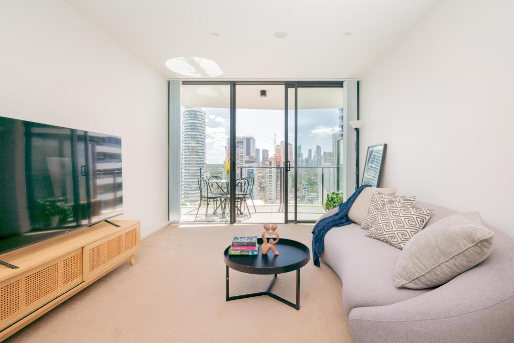 a living room with a couch and a tv and a table at Modern Broadbeach 2BR Apartment - Pet Friendly in Gold Coast