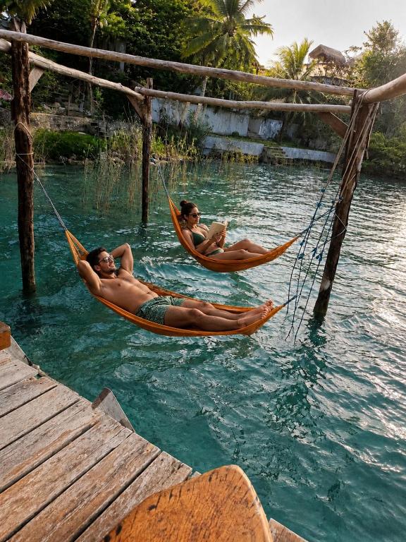 three people are laying in hammocks in the water at Villas Karalv in Bacalar