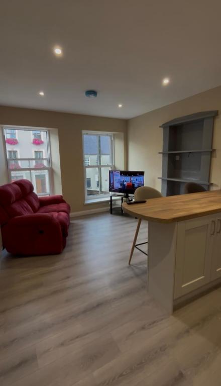 a living room with a red couch and a table at Sperrin Way Apartment in Newtownstewart