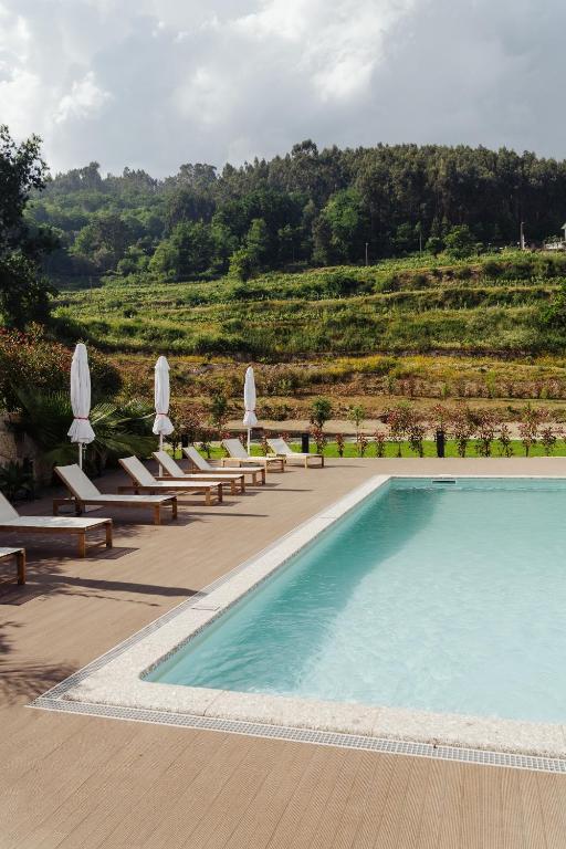 a swimming pool with lounge chairs and umbrellas at Quinta de Reis in Ponte da Barca