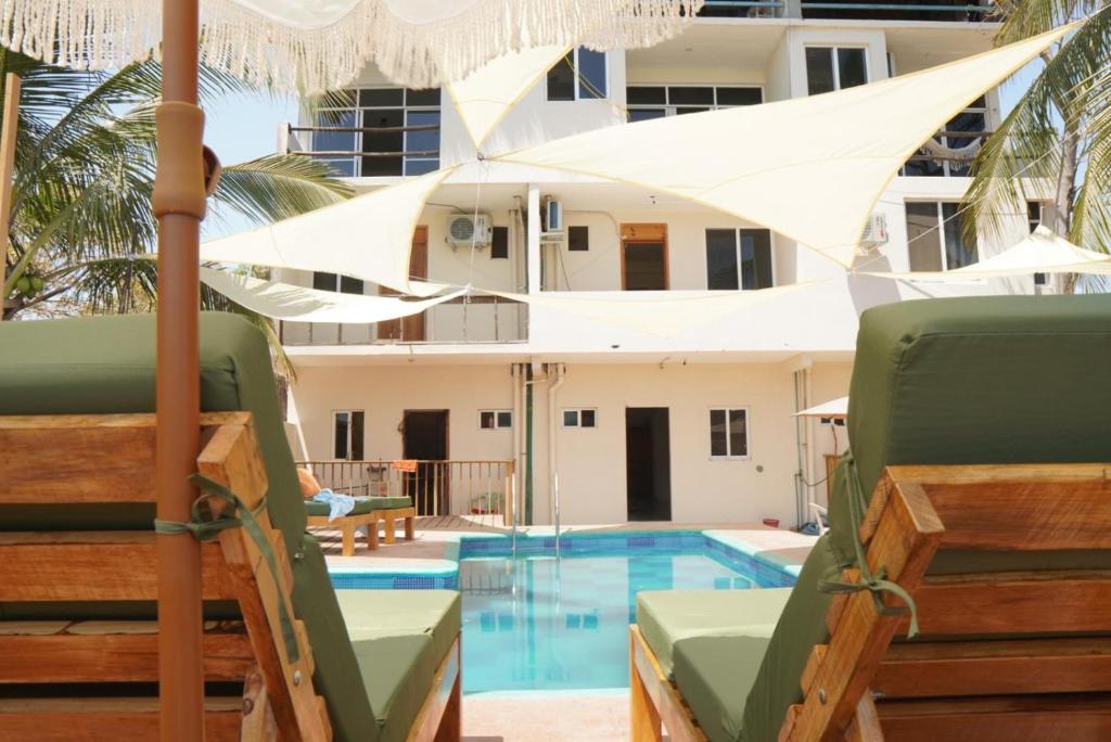 a pool with chairs and an umbrella next to a building at Montero Residences in Brisas de Zicatela