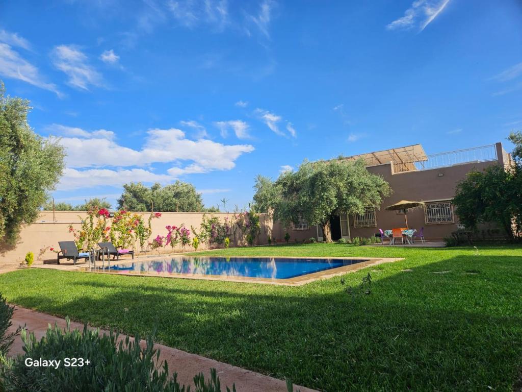 a yard with a swimming pool in front of a house at Villa du bonheur Chambres d'hote in Ouled el guerne