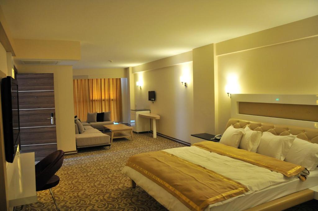 Una habitación de hotel con una cama grande y una sala de estar. en Ozpark Hotel, en Aksehir