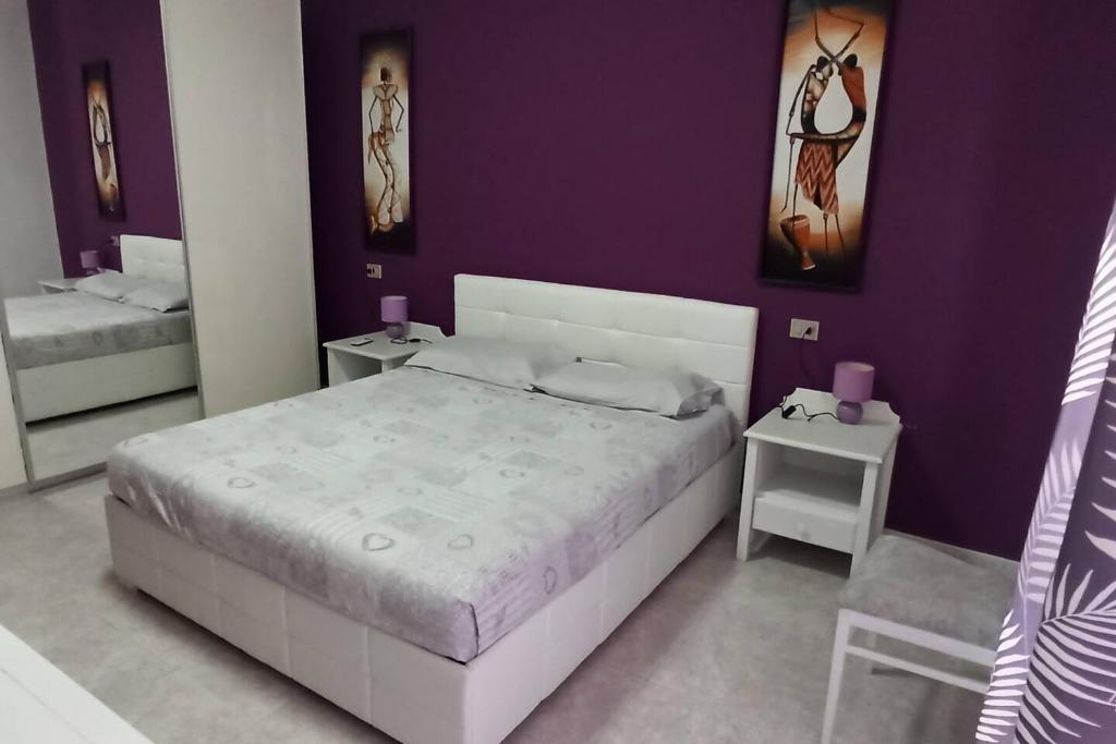 a bedroom with a white bed and purple walls at Mare e Città in Selargius