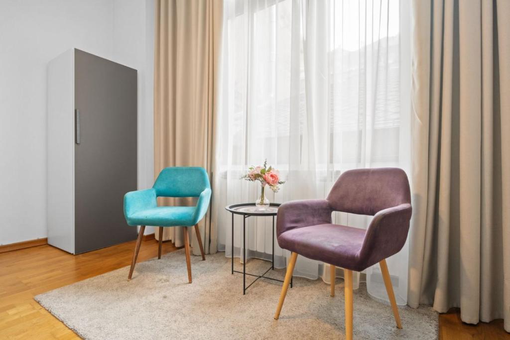 two chairs and a table in a room with a window at Villa Boema- with parking for large business groups in Bucharest