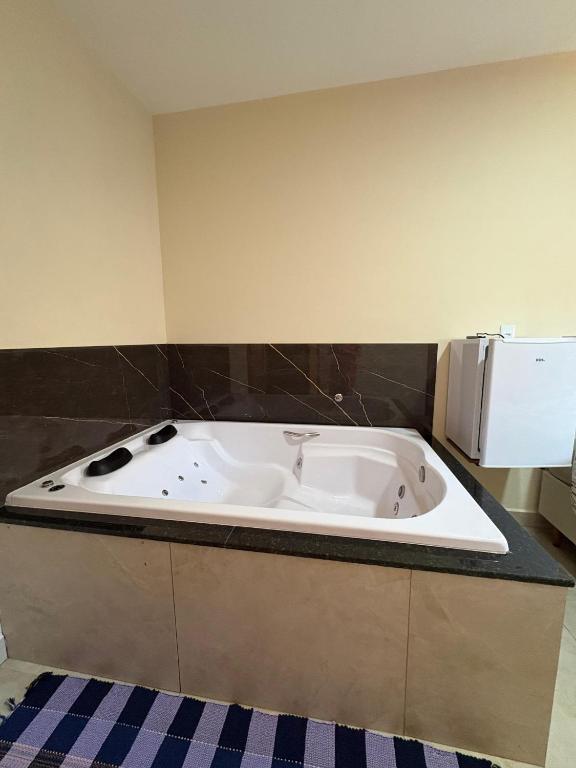 a white bath tub in a room with a microwave at Pousada Nascer da Lua in São Thomé das Letras