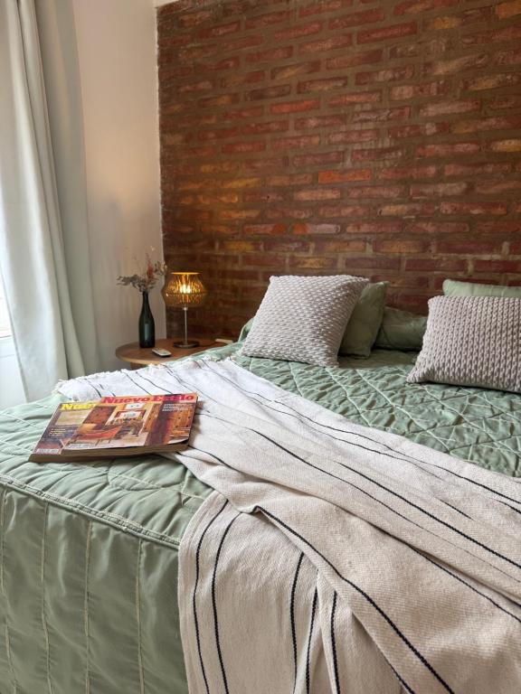 a bed with a book on it with a brick wall at Complejo Pampa in Santa Rosa