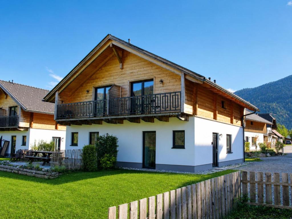 a large wooden house with a fence and a yard at Rattendorf 11B in Rattendorf