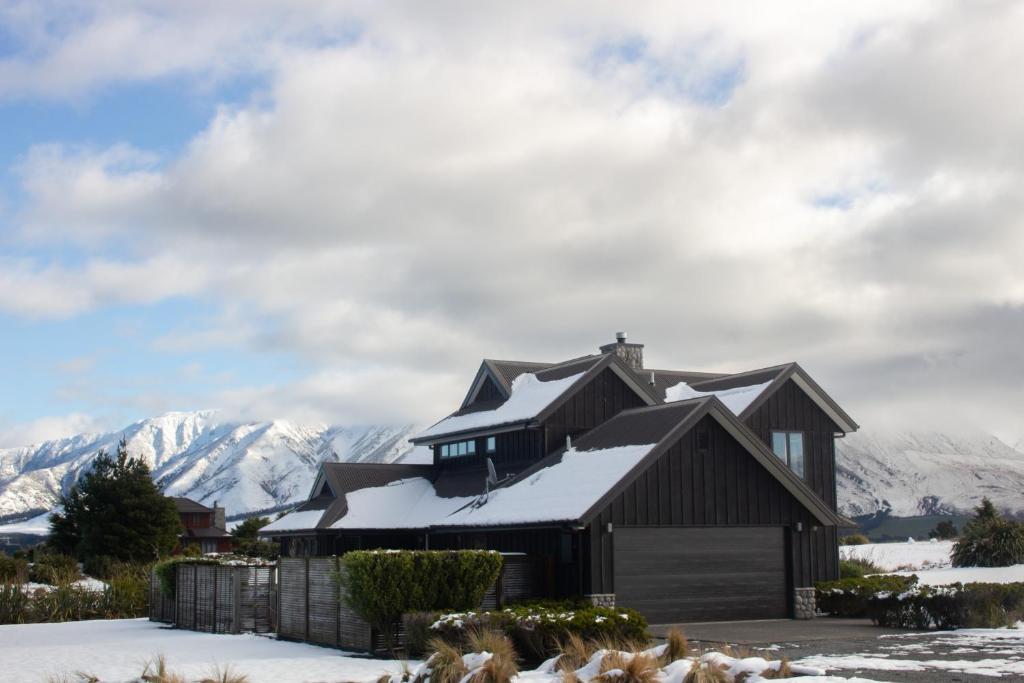 a house in the snow with mountains in the background at Yuki's Chalet - Terrace Downs in Windwhistle
