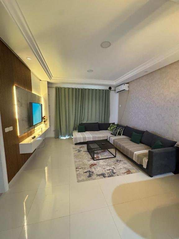 a large living room with a couch and a tv at Apt A3 in Siliana