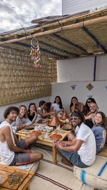 a group of people sitting around a table at Emallayan Hostel in Imsouane