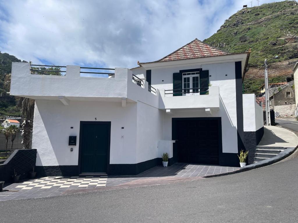 a white house with a hill in the background at Rdj A in Porto Moniz