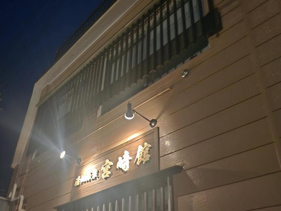 a sign on the side of a building with lights at 湯畑源泉宮崎館 in Kusatsu