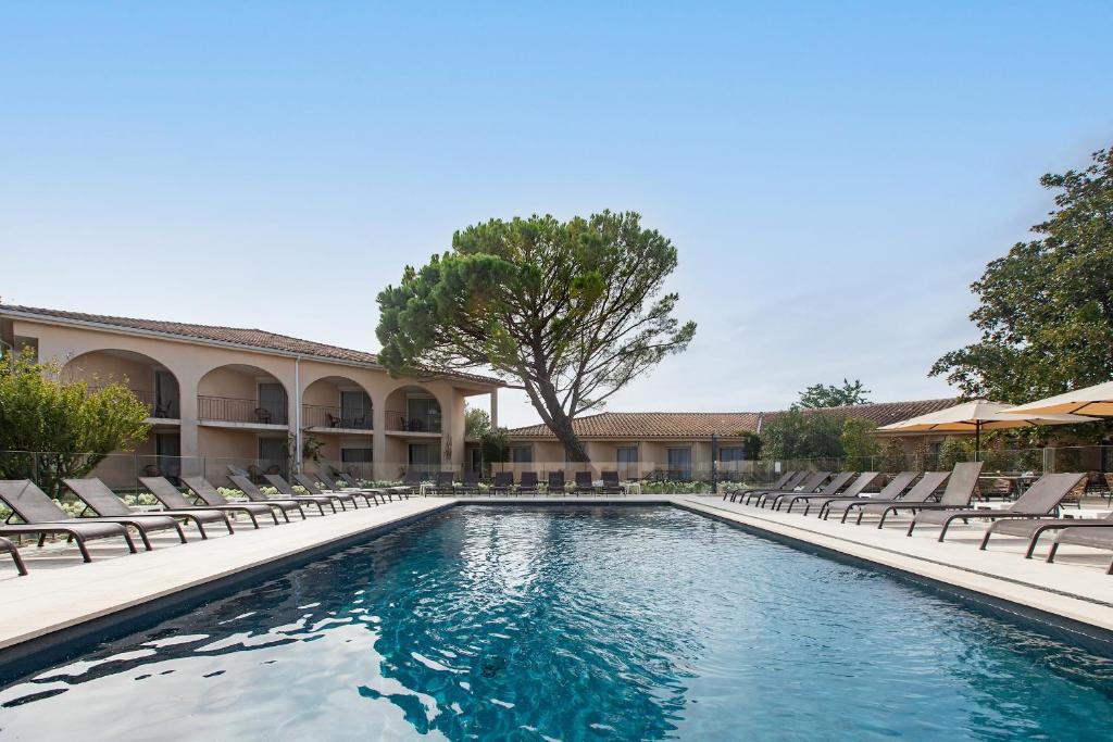 a swimming pool with lounge chairs and a building at Golden Tulip Avignon Le Paradou in Avignon