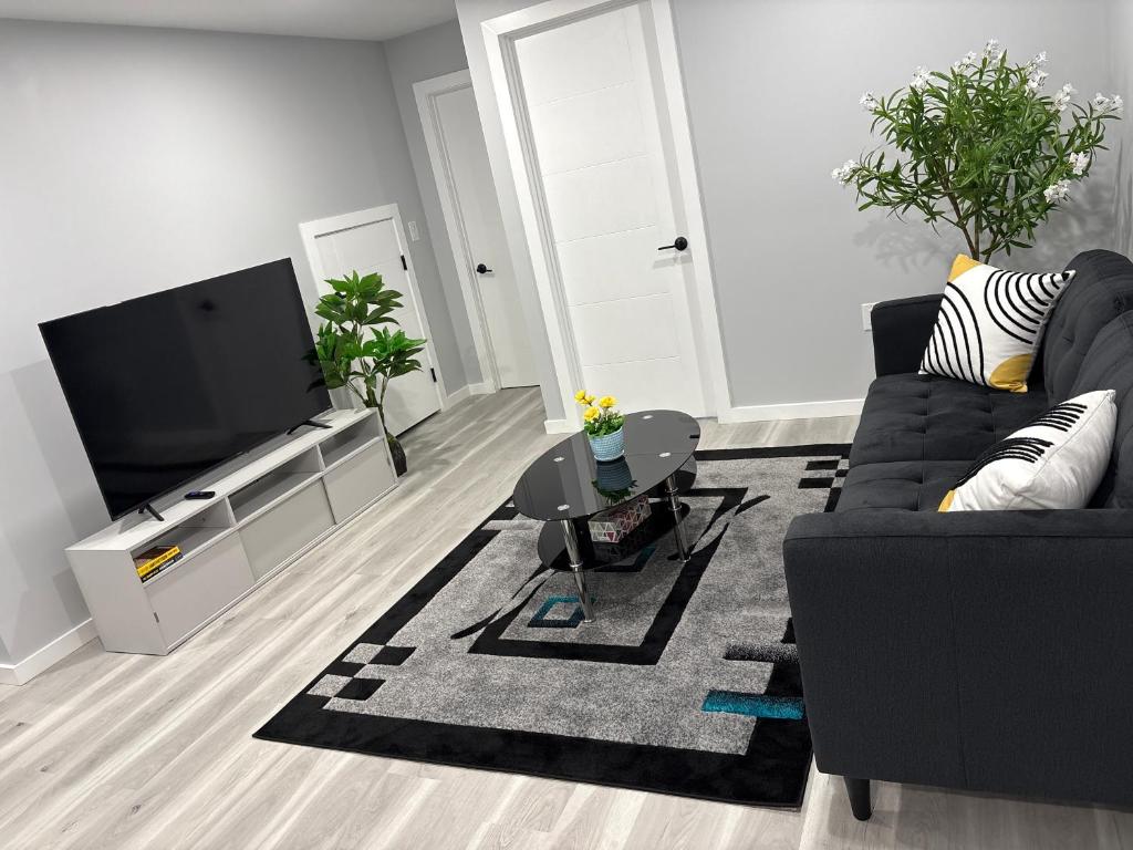 a living room with a black couch and a flat screen tv at Spacious Entire Basement Suite with Free Parking Self Check In in Winnipeg