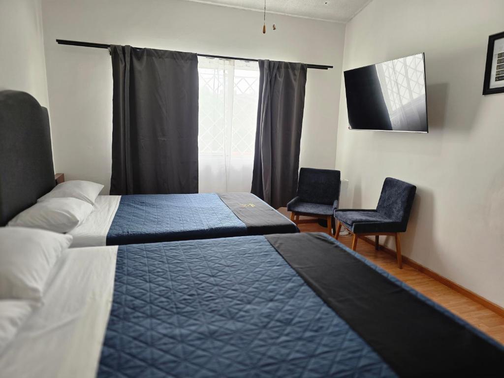a bedroom with two beds and two chairs and a window at 25 Habitación doble cama in Miravalle