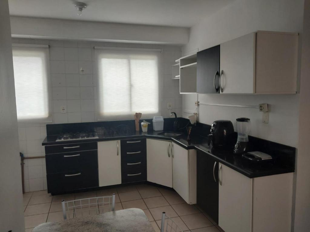 a kitchen with white cabinets and black counter tops at Apto terreo bem arejado e iluminado in Gravataí