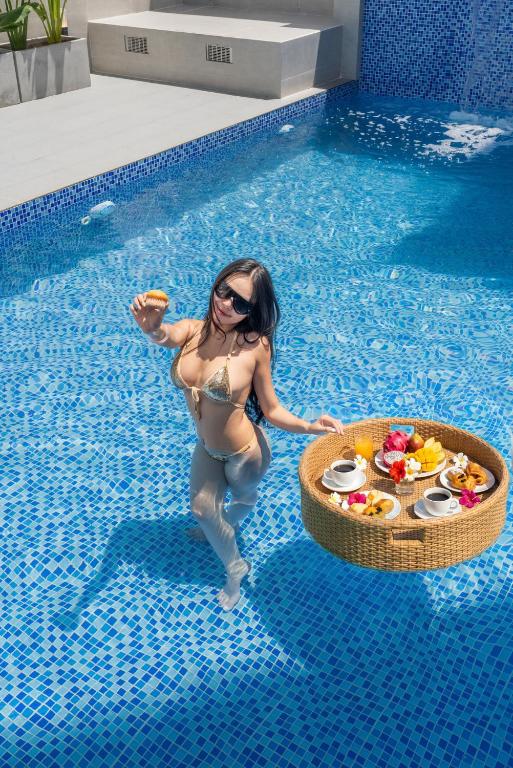 a woman in a swimming pool with a tray of food at KLY Hotel & Retreat in Vung Tau