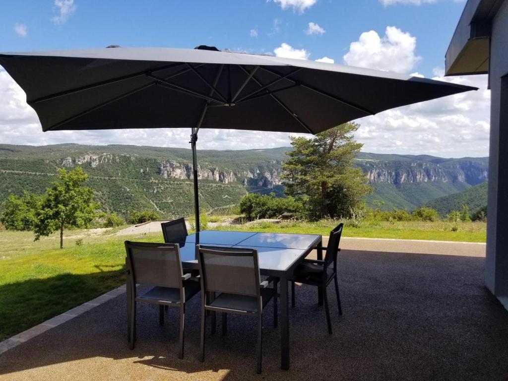a table and chairs under an umbrella on a patio at Le balcon des gorges in Saint-Rome-de-Dolan