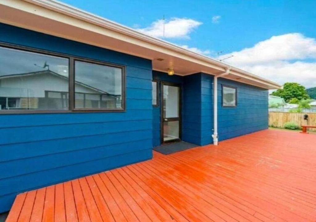 a blue house with a wooden deck at Stylish Trentham Retreat in Upper Hutt