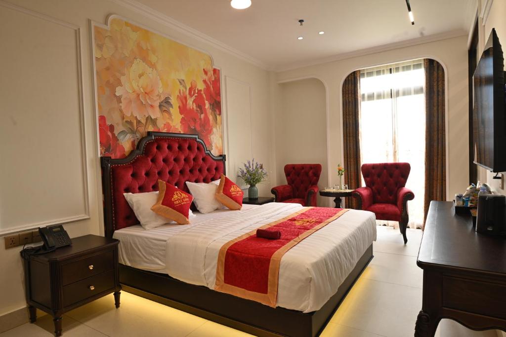 a bedroom with a large bed and two red chairs at Nhật Long Hotel in Giap Ninh Binh