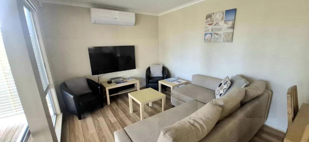 a living room with a couch and a flat screen tv at Little Sanctuary by Book Jervis Bay - Your Perfect Getaway, A Short Stroll to Palm Beach in Sanctuary Point