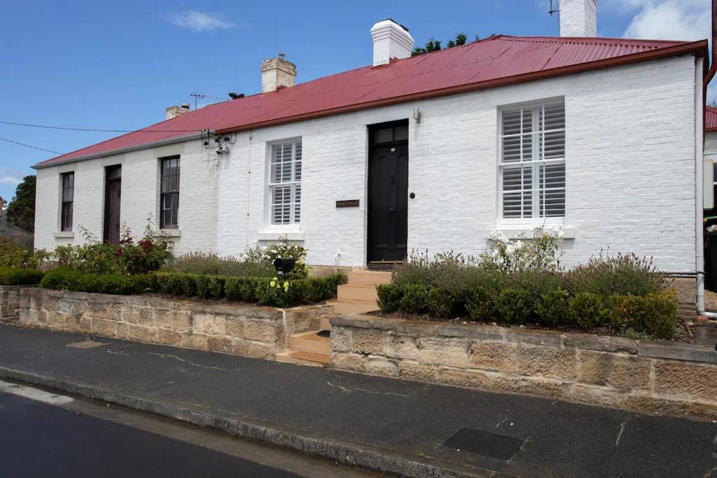 a white house with a red roof on a street at Tamara Cottage Historic Warmth in Hobart