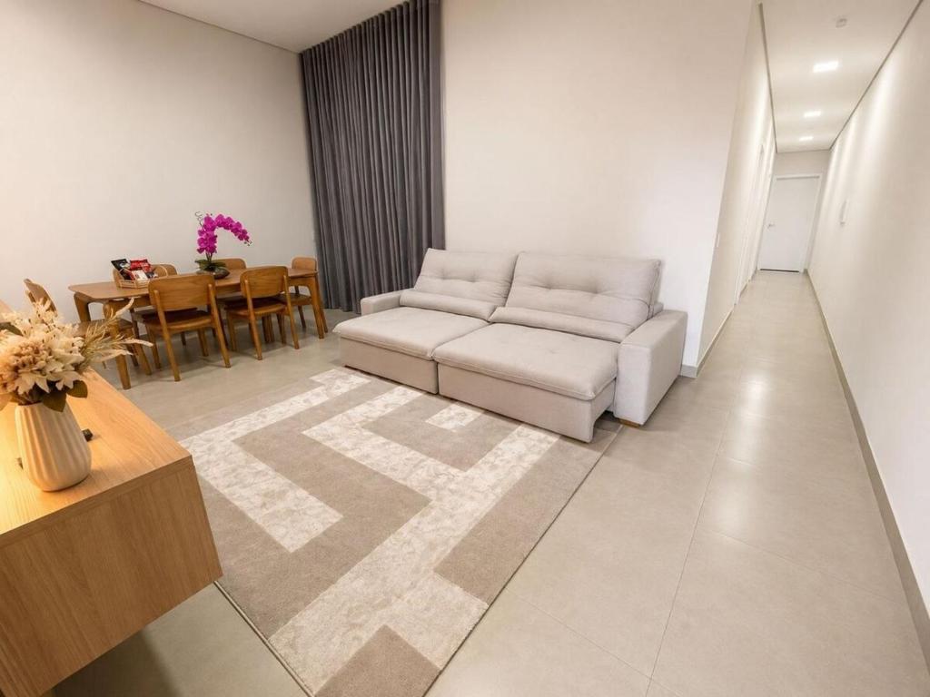 a living room with a white couch and a table at Casa Premium NOVA - Perto do Shopping em SINOP in Sinop