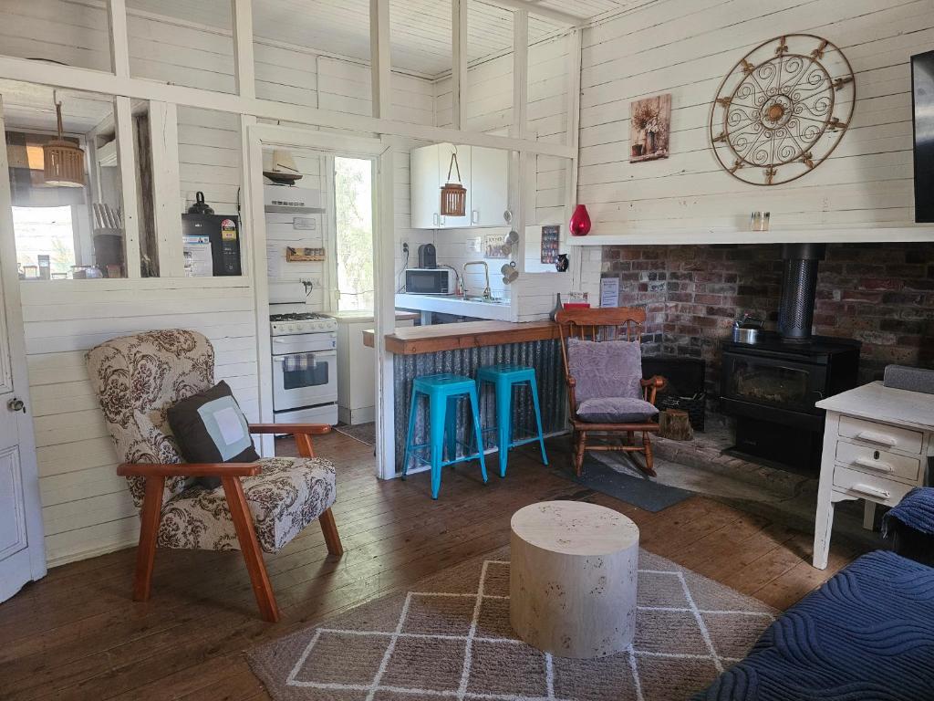 a living room with a fireplace and a table and chairs at FarmStay Pepperina & Bird Sanctuary in Bendemeer
