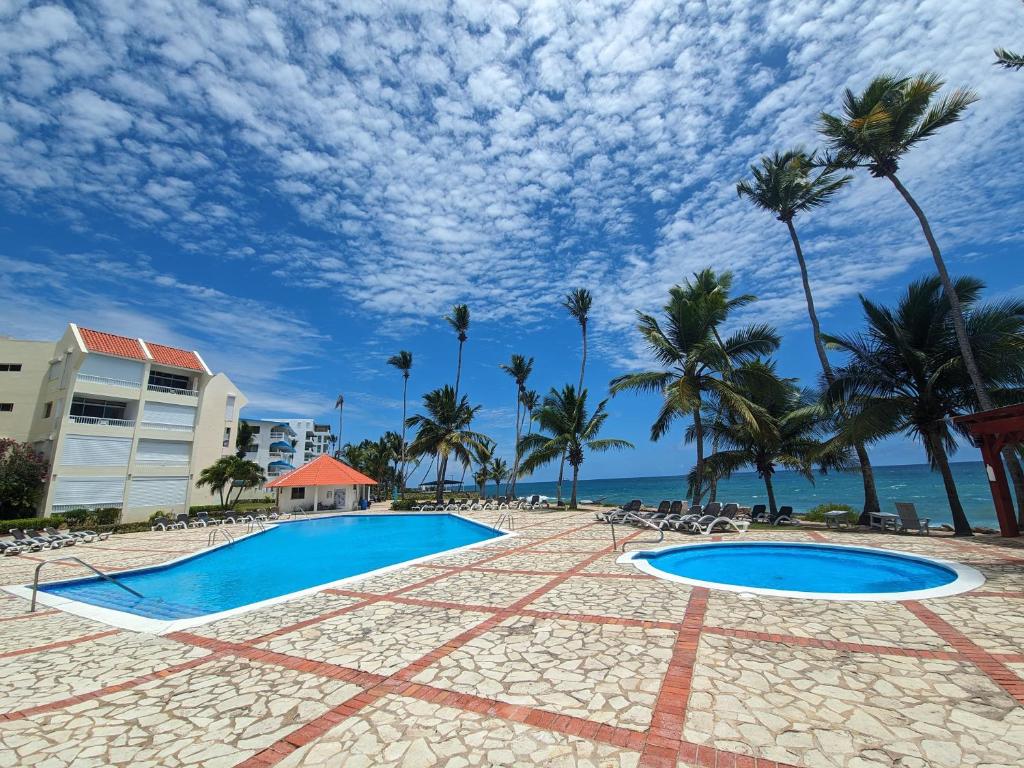 a resort swimming pool with palm trees and the ocean at Nice View always available in Juan Dolio