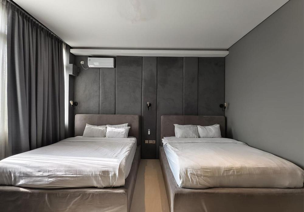 two beds sitting next to each other in a bedroom at Ohana Suites Yogyakarta in Yogyakarta