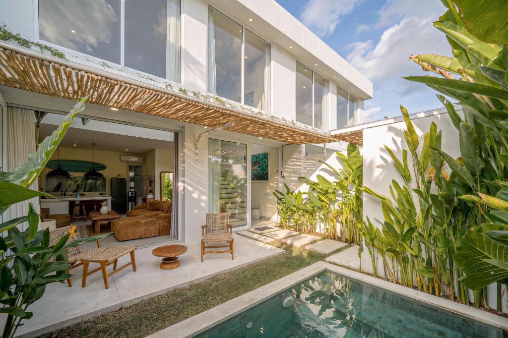 a house with a swimming pool and a living room at Villa Pia Pererenan in Cemagi