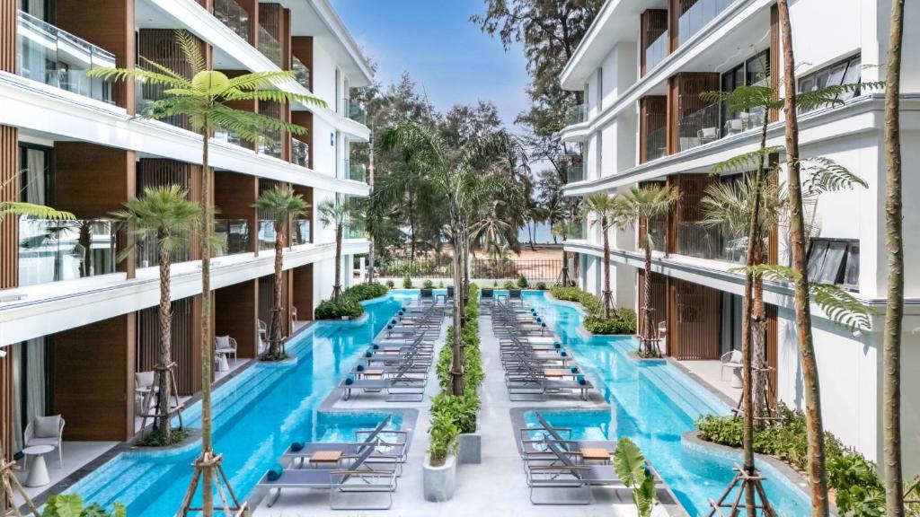 an image of a hotel courtyard with chairs and palm trees at Beachfront Luxury Apartment Bangtao Phuket in Bang Tao Beach