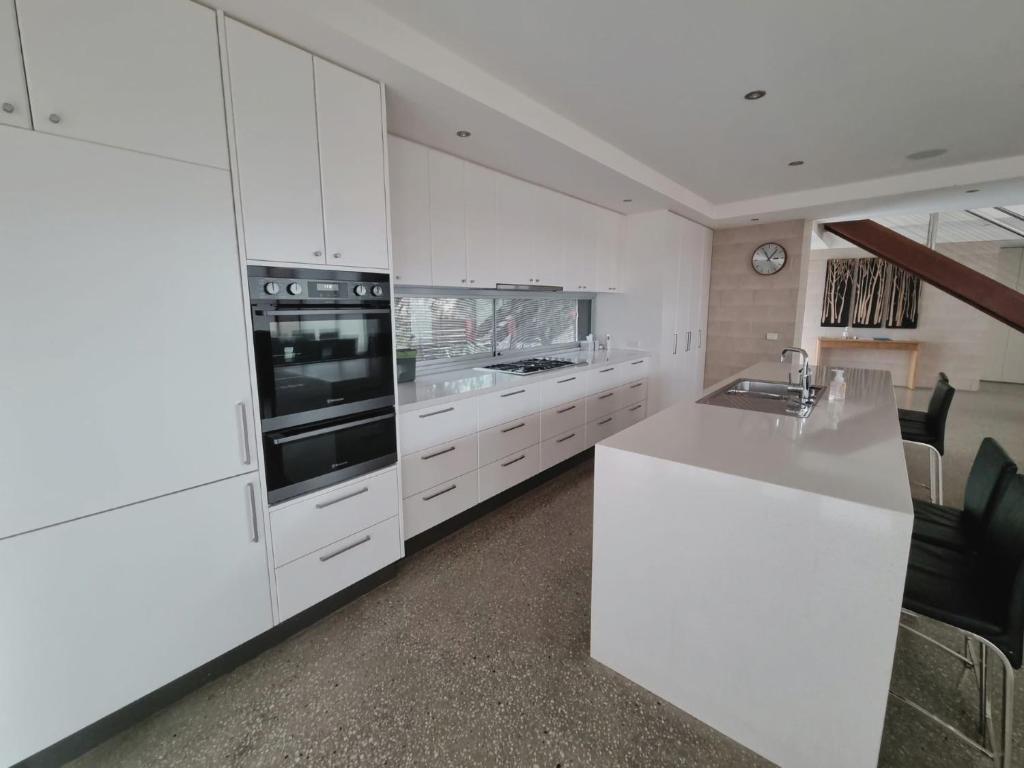 a kitchen with white cabinets and a white counter top at Beach Haven in Point Lonsdale