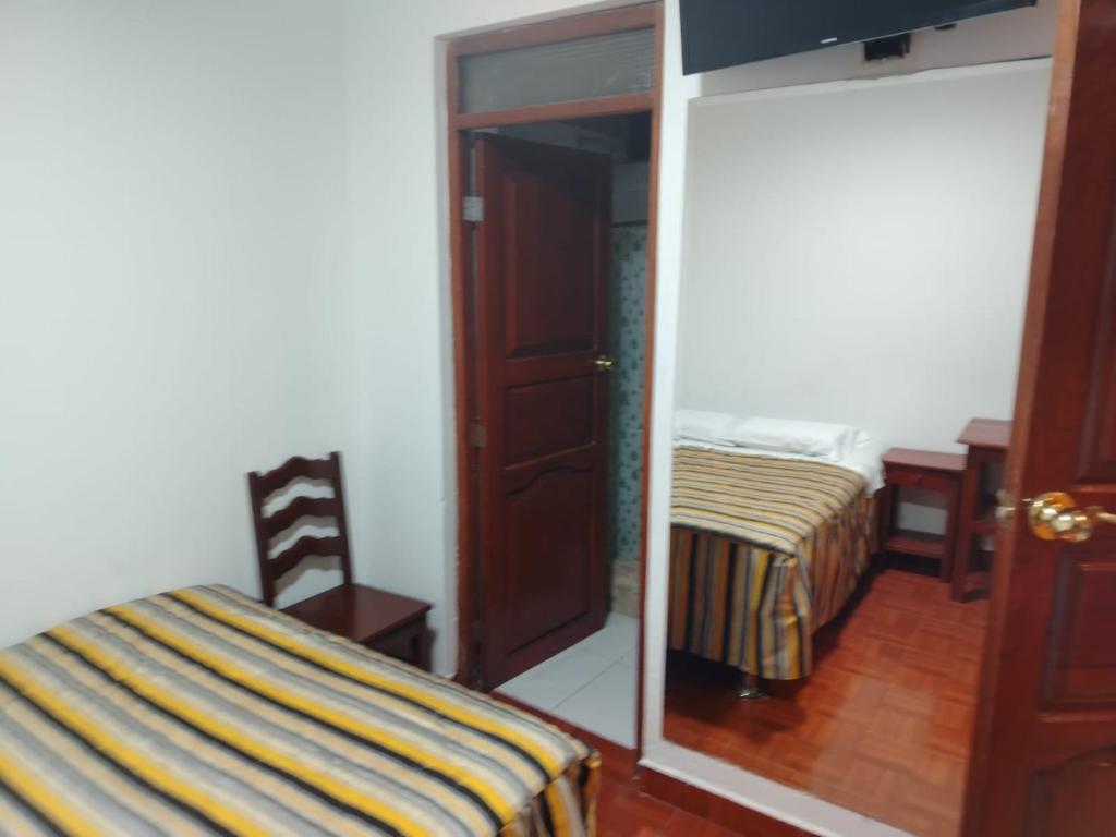 a bedroom with a mirror next to a bed and a door at HOTEL Omar in Ayacucho