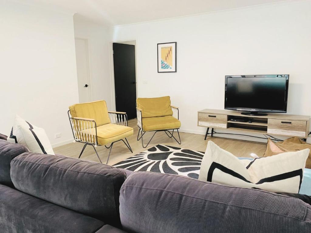 a living room with a couch and chairs and a flat screen tv at Buckley s 10 in Point Lonsdale